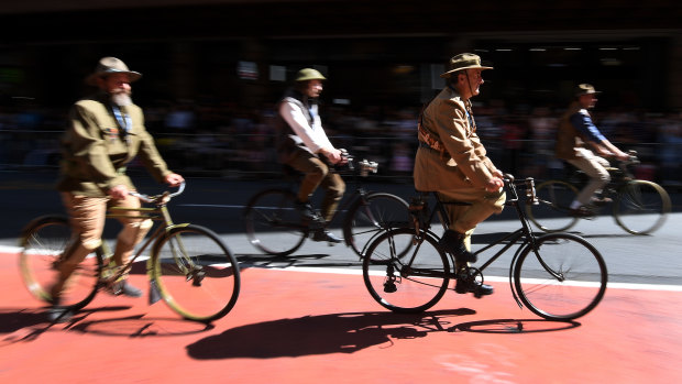 Men dressed in WWI uniform on bicycles pedal through Brisbane's streets.