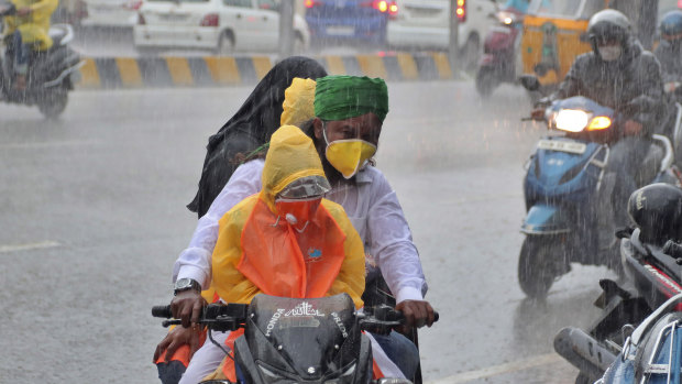 An Indian family wearing face masks navigate monsoon rains in Hyderabad, India.