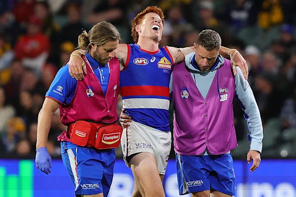 Bulldogs midfielder Ed Richards is helped from the ground.