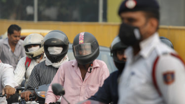 Motorcyclists cover their faces to save themselves from air pollution as they wait at a crossing in New Delhi, India.
