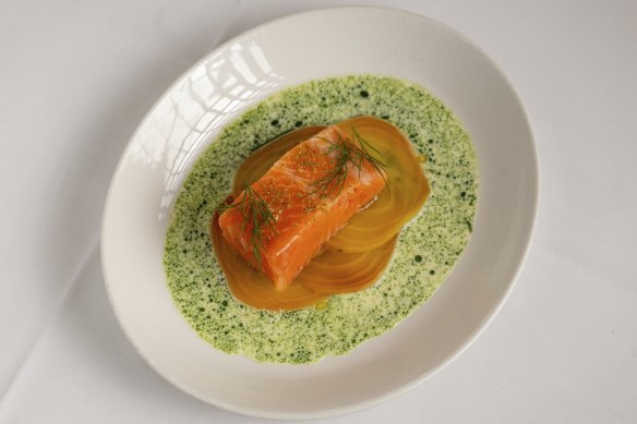 Confit salmon is plated on thin slices of golden beetroot, with a moat of dill crema.