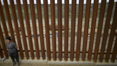 A Mexican woman stands at a newly-replaced section of border wall in Tijuana.