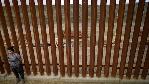 A Mexican woman stands at a newly-replaced section of border wall in Tijuana.