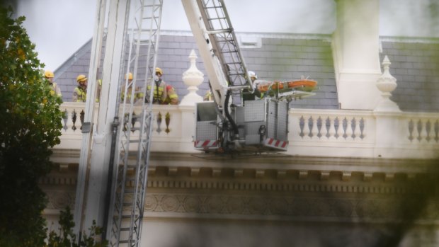 The Government House intruder is brought down from the roof in a rescue stretcher.