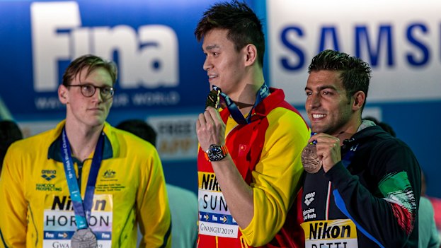 Mack Horton (left) makes his point as Sun Yang (centre) accepts his gold medal at the 2019 world championships.