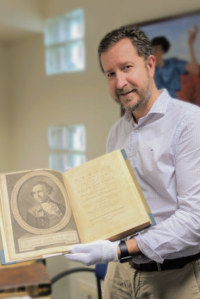 Fryer Library manager Simon Farley holding the rare Captain James Cook book to be auctioned at the University of Queensland.