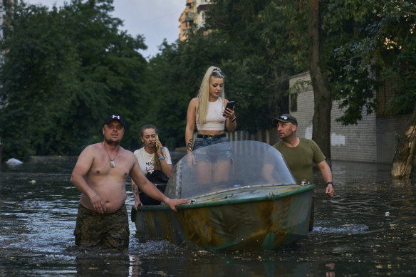 Ukrayna'nın Herson kentinde büyük bir barajın yıkılmasının ardından sular altında kalan bir mahalleden sakinleri taşıyan tekneler tahliye ediliyor.