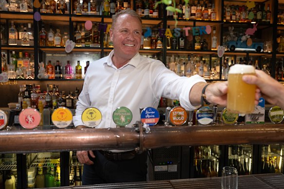 Nationals candidate for the federal seat of Bendigo, Andrew Lethlean, handing over a beer at his bar.