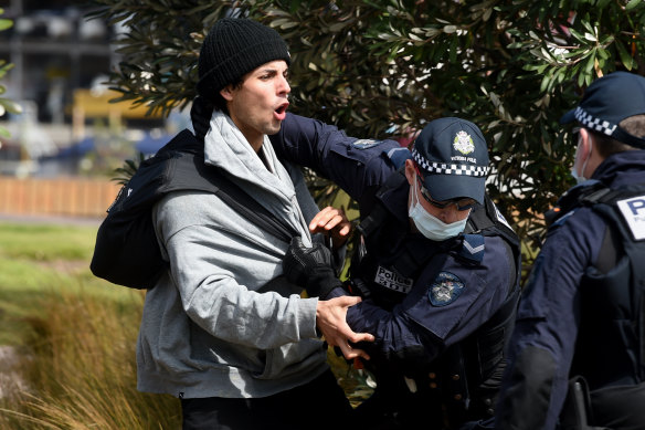 Victoria Police members arrest a protester along the St Kilda foreshore on Saturday.