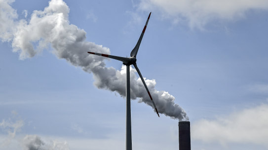 A coal-fired plant chimney and a wind farm. 
