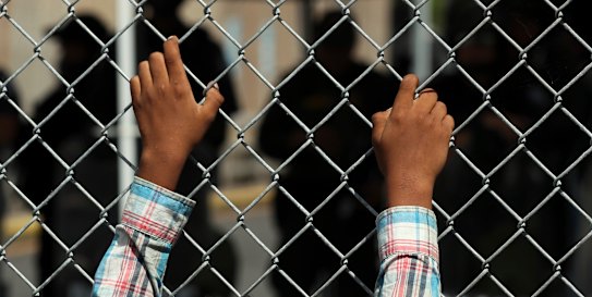 A migrant leans on a fence of the Gateway International Bridge that connects Matamoros in Mexico with Brownsville in Texas in the US.