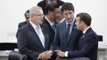 President of China Xi Jinping walks past as Scott Morrison talks with Canada's Justin Trudeau and France's Emmanuel Macron, who supported the PM's campaign regarding Facebook.