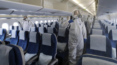 Flying in the time of COVID-19: Workers in protective suits disinfect a plane.