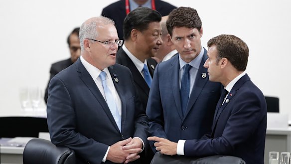 President of China Xi Jinping walks past as Scott Morrison talks with Canada's Justin Trudeau and France's Emmanuel Macron, who supported the PM's campaign regarding Facebook.