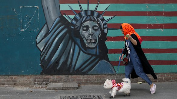 A woman walks her dog past an anti-US mural painted on the wall of the former American embassy in Tehran, on Tuesday.