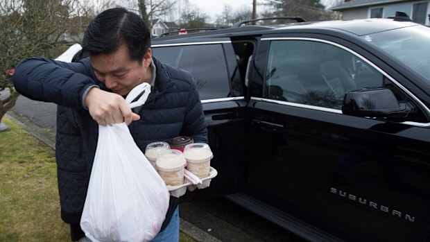 A man tries to shield his face as he arrives at the home of Huawei CFO Meng Wanzhou in Vancouver. She is out on bail and expected back in court on February 6.