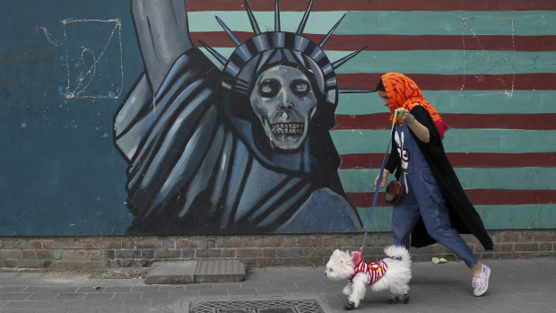 A woman walks her dog past an anti-US mural painted on the wall of the former American embassy in Tehran, on Tuesday.