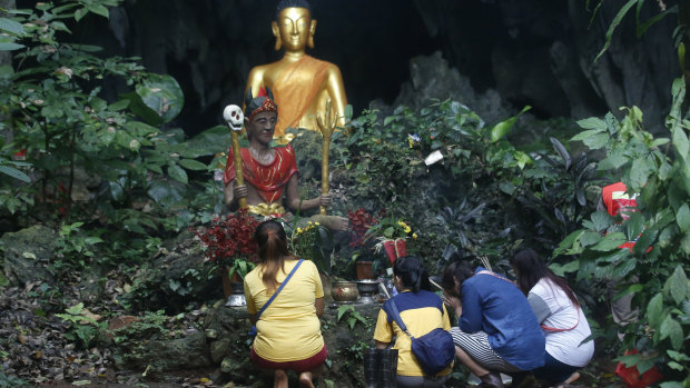 Family members pray in front of a Buddhist statue near a cave where 12 boys and their soccer coach have been trapped since June 23, in Mae Sai, Chiang Rai province.