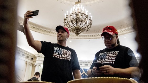 Trump supporters film themselves during a live stream before the start of a House Judiciary Committee markup of the articles of impeachment against US President Donald Trump.