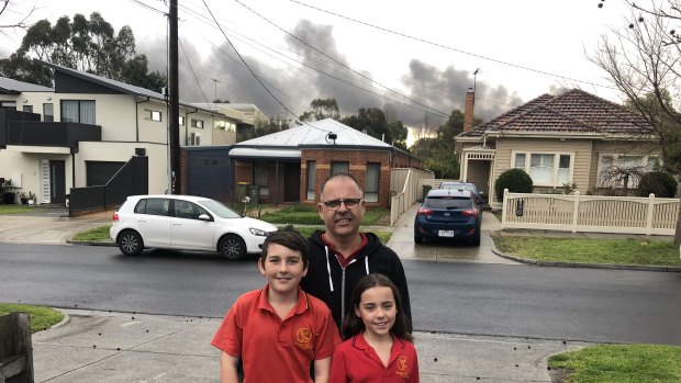 Dave Stembridge with his children Will and Isla and, behind them, the plume of smoke from the factory fire.