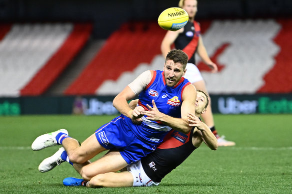 Marcus Bontempelli gets the ball away while being tackled by Devon Smith.