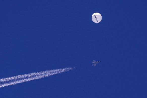 A large balloon drifts above the Atlantic Ocean, just off the coast of South Carolina, with a fighter jet and its contrail seen below it, shortly before it was struck by a missile from an F-22 fighter.