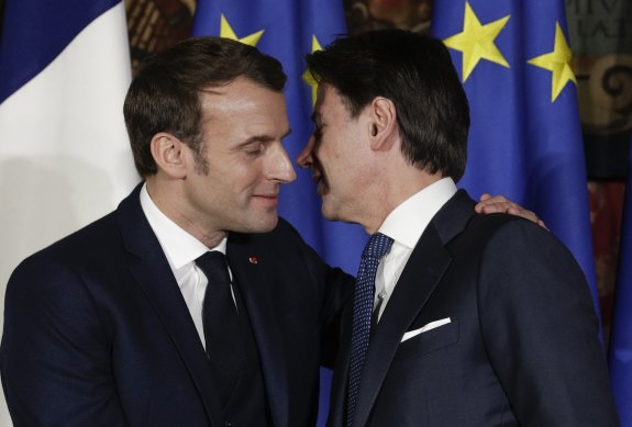French President Emmanuel Macron puts his arm around Italian Prime Minister Giuseppe Conte as he shakes his hand and kisses him on both cheeks in Naples on February 27.