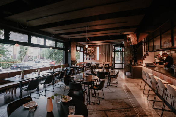 The room features a long banquette down one side, with a bar and DJ booth down the other.