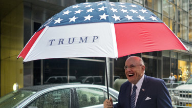Former New York City mayor Rudy Giuliani leaves Trump Tower bearing an umbrella.
