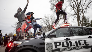 Protesters jump on police vehicles near the site of a shooting involving a police officer in the city of Brooklyn Center, Minnesota.