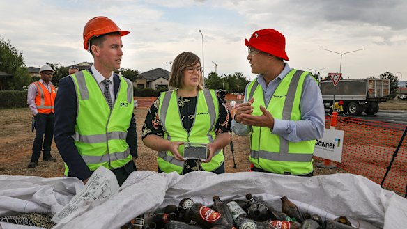 Executive general manager of road services at Downer Dante Cremasco, right, shows roads minister Chris Steel and member for Yerrabi Suzanne Orr the kind of glass used in the asphalt trial.