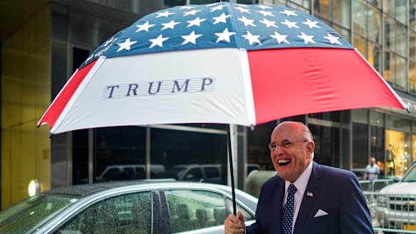 Former New York City mayor Rudy Giuliani leaves Trump Tower bearing an umbrella.
