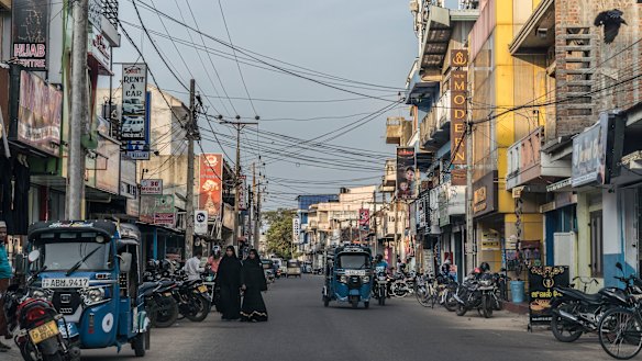 Women wearing abayas walk down a street in Kattankudy, the hometown of Zaharan Hashim.