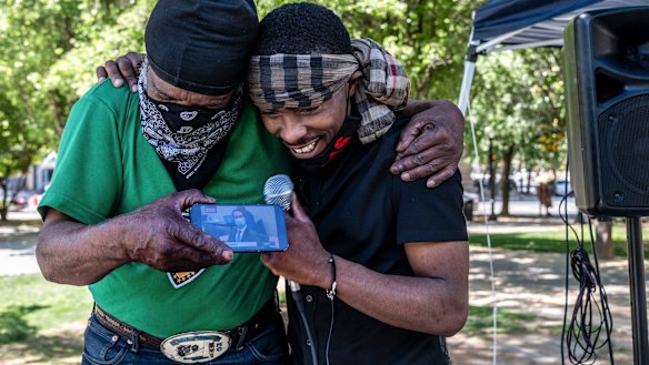 Stevante Clark, right, brother of Stephon Clark who was fatally shot by Sacramento Police, is hugged by his cousin Steven Ray Collins in Sacramento California, as they listen to the Chauvin verdict on their phone.