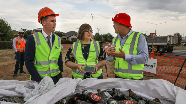 Executive general manager of road services at Downer Dante Cremasco, right, shows roads minister Chris Steel and member for Yerrabi Suzanne Orr the kind of glass used in the asphalt trial.