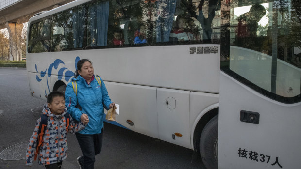  A mother brings her son to the Real Boys Club bus that will take enrolled boys to the sports school in Beijing.