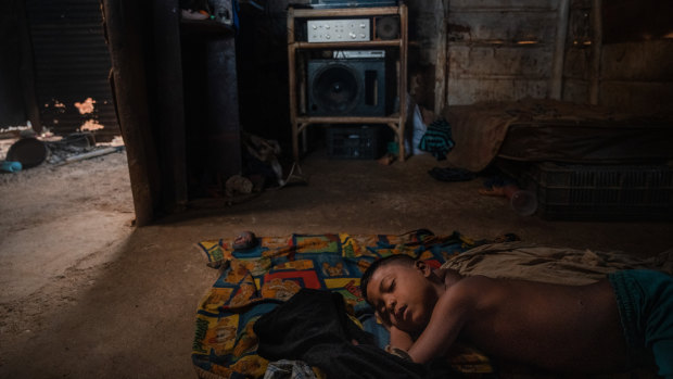 Dioger Lares, 7, fell asleep watching the television his father repaired with the money he traded for gold earrings, in Guaca, Venezuela.