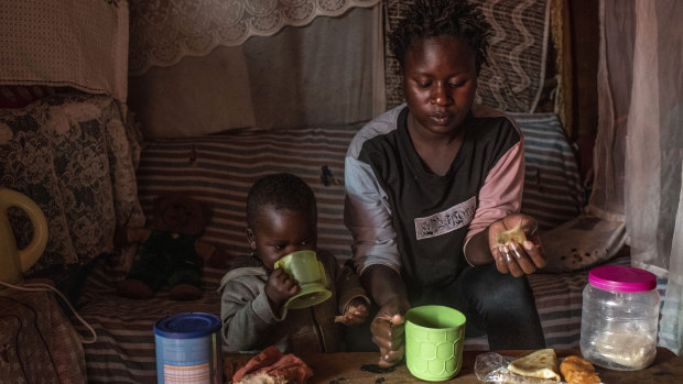 Sharon Mbone has breakfast with her son, who has been ill and taking antibiotics, at home in Kibera, Nairobi.
