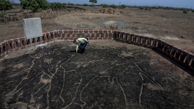 Amateur archaeologist Sudhir Risbud examines a petroglyph of an elephant.