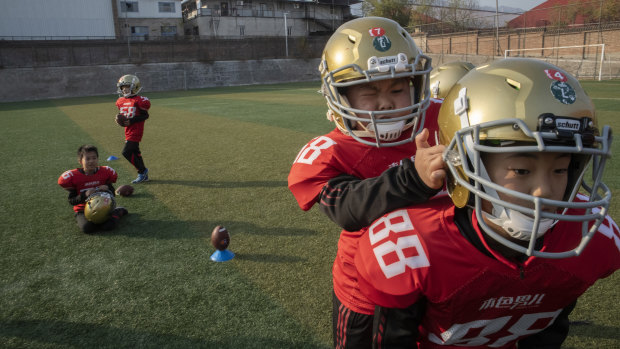 Students help each other put on gridiron helmets.