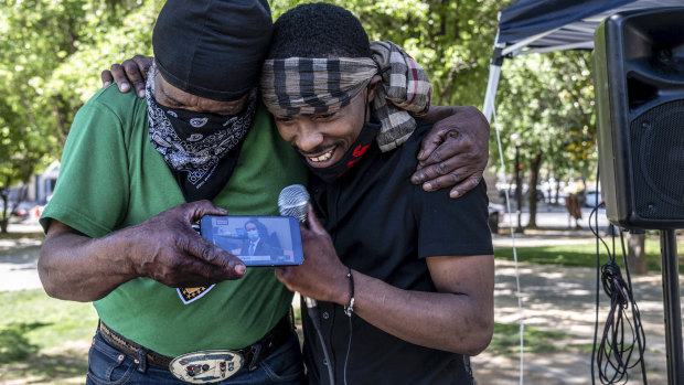 Stevante Clark, right, brother of Stephon Clark who was fatally shot by Sacramento Police, is hugged by his cousin Steven Ray Collins in Sacramento California, as they listen to the Chauvin verdict on their phone.