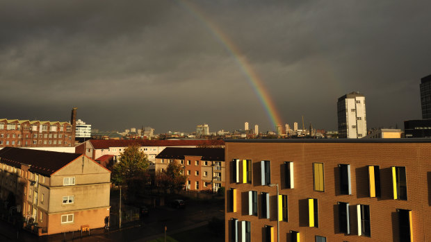 Dark brooding skies over Glasgow city centre lit up by sunshine and a rainbow.