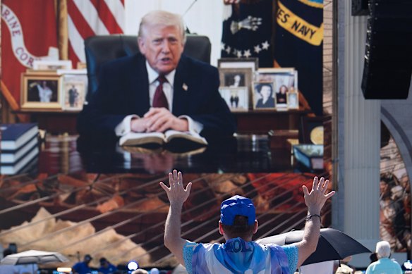 Una persona adora mentre un videomessaggio registrato del presidente Donald Trump viene riprodotto al Rededicate 250. 