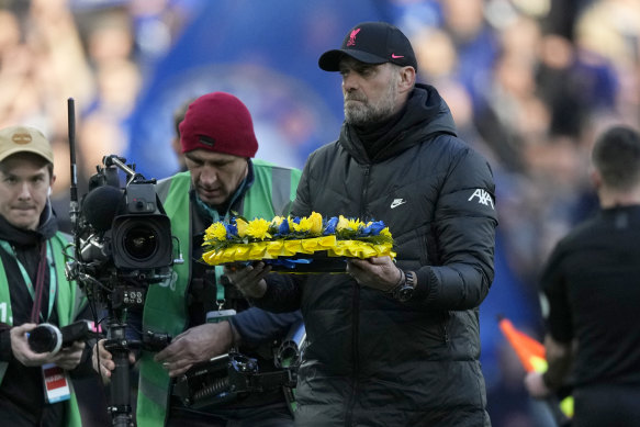 Liverpool’s manager Jurgen Klopp holds a wreath in the Ukrainian flag before the start of the English League Cup final.