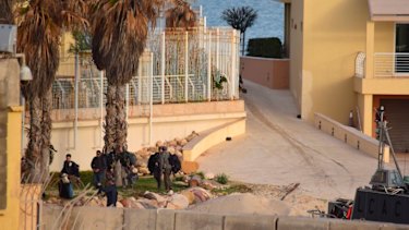 People move around the landing area as a US amphibious hovercraft, right, prepares to depart with evacuees from Janzur, west of Tripoli, Libya.