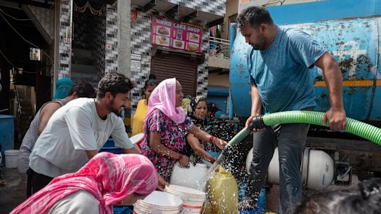 Containers are filled from a water tanker in a New Delhi slum this month.