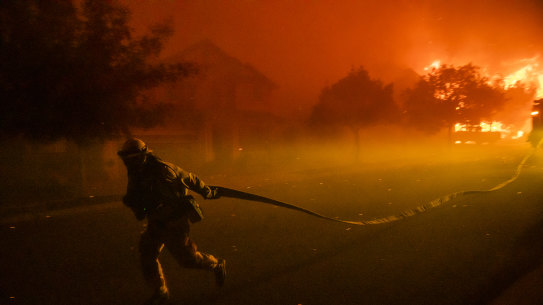 A firefighters drags a hose as he defends the Skyhawk Park neighbourhood of East Santa Rosa.