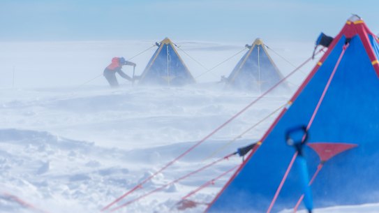 Dr Yixi Zheng of the British Antarctic Survey clears snow from her tent on Thwaites Glacier.