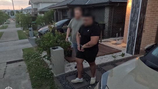 Police take one of the alleged “kill car” team into custody at Oran Park on Thursday