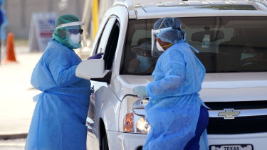 Healthcare workers administer COVID-19 tests at a drive-through site in San Antonio, Texas.